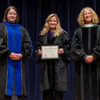 Awardee posing with award, with Provost Drake and Christine Rener